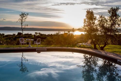 a reflection of the sunset in a pool with a table and chairs at Agriturismo Parco di Canuleio - con vista sul Lago in Bolsena