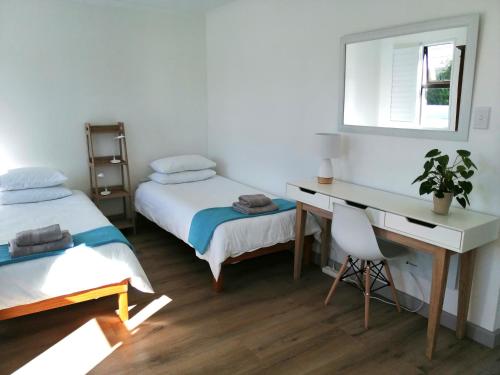 Zimmer mit 2 Betten, einem Schreibtisch und einem Spiegel in der Unterkunft Malmesbury Self-catering in Malmesbury