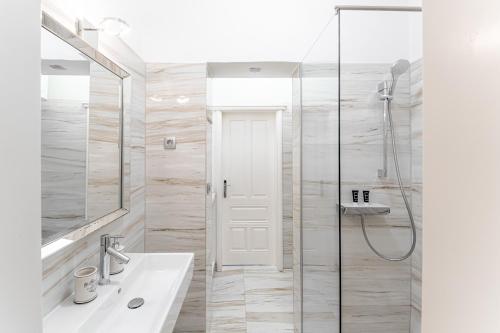 a white bathroom with a shower and a sink at Kenti Residence in Ljubljana