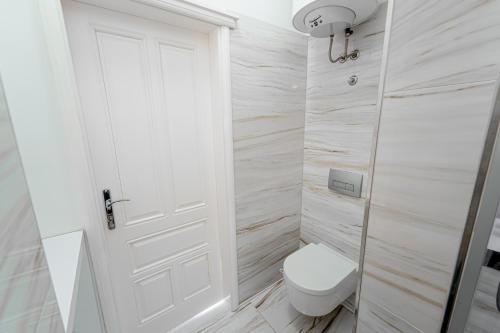 a white bathroom with a toilet and a door at Kenti Residence in Ljubljana