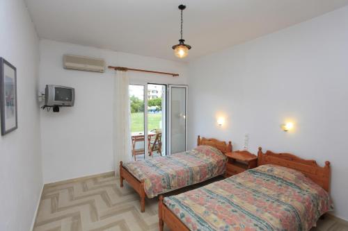 a bedroom with two beds and a tv on the wall at Yiannis Studios in Troulos