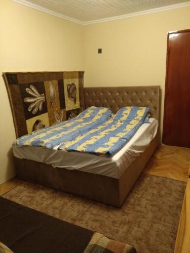 a bedroom with a bed with a blue and yellow blanket at Erdei Vendégház in Nagyesztergár