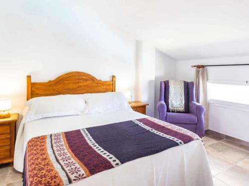a bedroom with a bed and a purple chair at Casa Puentelata in Dúrcal