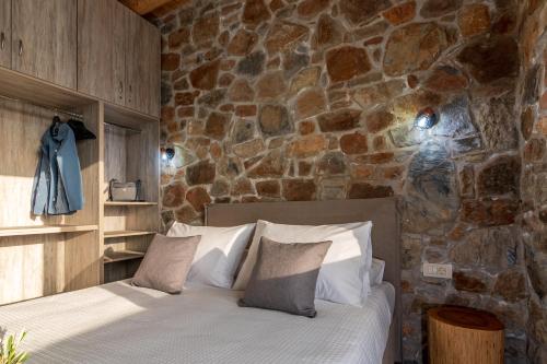 a bed in a room with a stone wall at The Rock *Peaceful Retreat House in Kámbos