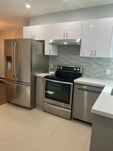 a kitchen with stainless steel appliances and white cabinets at Flowealth Property in Toronto