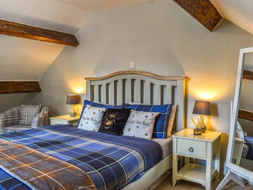 a bedroom with a blue bed and two night stands at Beeswax Cottage in Dalton in Furness