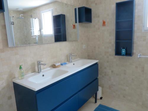 y baño con lavabo azul y espejo. en Le vieux chai, en Sainte-Marie-de-Ré