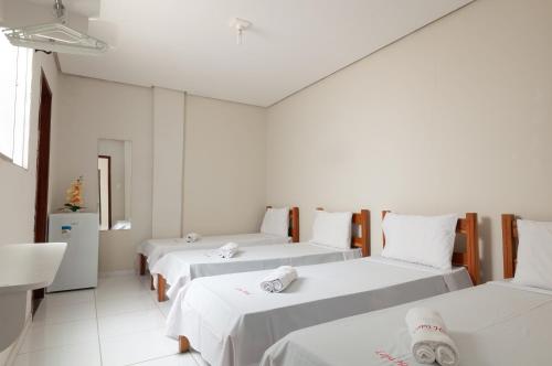 a room with three beds with white sheets at Lapa Hotel in Bom Jesus da Lapa