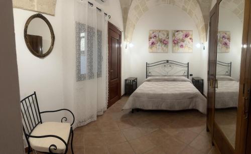 1 dormitorio con cama, espejo y silla en Casa Vacanza - L’ Antica Torre, en Maruggio