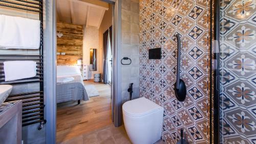 uma casa de banho com WC e uma parede com azulejos em COTTAGE VIOLAPO 6&2, Emma Villas em Civitella Marittima