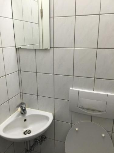 a white bathroom with a sink and a toilet at Carli's Bed-No-Breakfast in Friedrichshafen