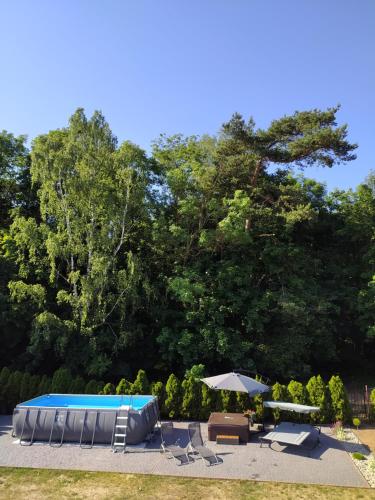 a pool with chairs and umbrellas in a yard at Pokoje Gościnne Ontario Mieroszyno in Jastrzębia Góra