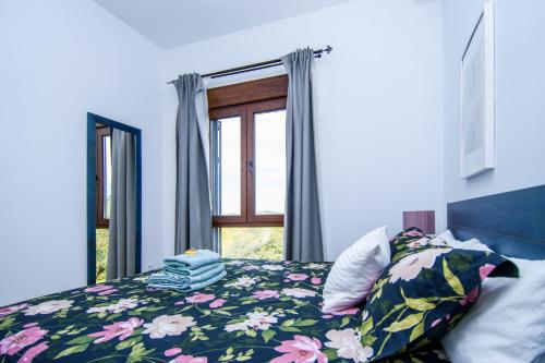 a bedroom with a bed with a floral comforter and a window at La Siesta del Naranjo in Monesterio