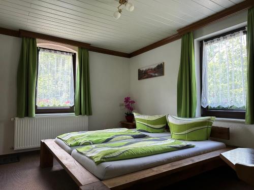 Schlafzimmer mit einem großen Bett und grünen Vorhängen in der Unterkunft Pension Bennelliebschänke in Seiffen