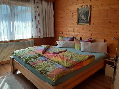 a bedroom with a bed with a wooden wall at Ferienwohnungen Pollhammer in Sankt Gallenkirch