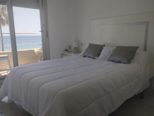 een slaapkamer met een groot wit bed en uitzicht op de oceaan bij Urbanización Marenia - Las Marinas, Denia in Denia
