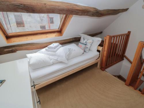 uma pequena cama com almofadas brancas e uma janela em Bramble Corner Cottage em Saltburn-by-the-Sea
