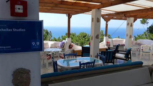 a patio with tables and chairs and the ocean at Kocheilas Studios in Gialiskari