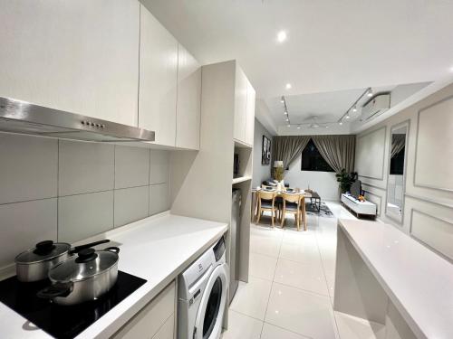 a kitchen with white appliances and a living room at KL Chambers Suites in Kuala Lumpur
