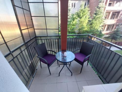 a balcony with a glass table and two chairs at Studio 61 Apartment in Ełk