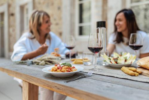 two women sitting at a table with food and wine at Corte Francigena in Montalcino
