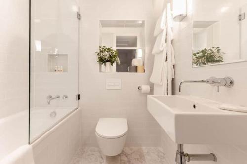 a white bathroom with a toilet and a sink at No 9 Rowden in Noss Mayo