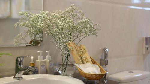 a bathroom sink with a vase of flowers and towels at FLORA HOME DALAT in Da Lat