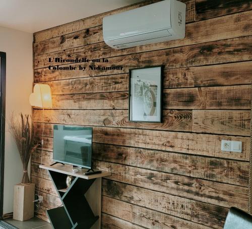 un mur recouvert de bois récupéré avec une télévision et un mur dans l'établissement NiD'Amour le Rossignol, à Bézenac