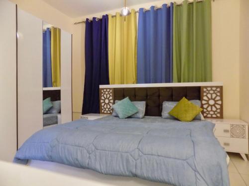 a bedroom with a large bed with colorful curtains at Al Canary Aparts in Ajman 