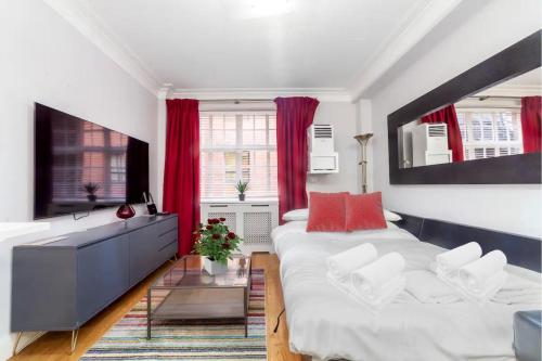 Modern Quiet 1 bed Flat -Mayfair في لندن: غرفة نوم بسرير كبير وستائر حمراء