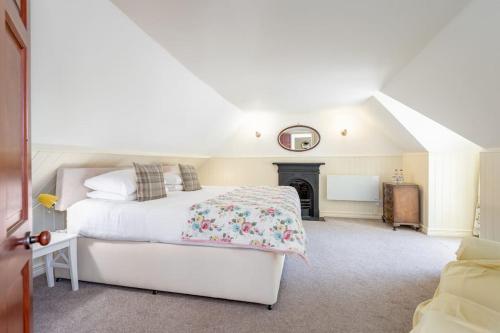 1 dormitorio con cama blanca y chimenea en Stable Cottage 2 bedrooms with gorgeous views, en Dunblane