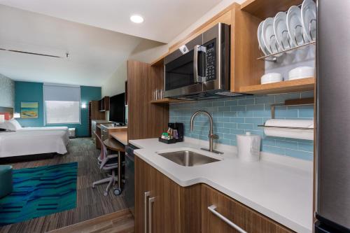a kitchen with a sink and a bed in a room at Home2 Suites By Hilton Vero Beach I-95 in West Vero Corridor