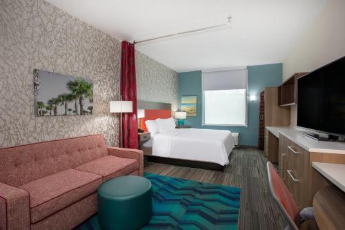 West Vero CorridorにあるHome2 Suites By Hilton Vero Beach I-95のベッドとソファ付きのホテルルーム