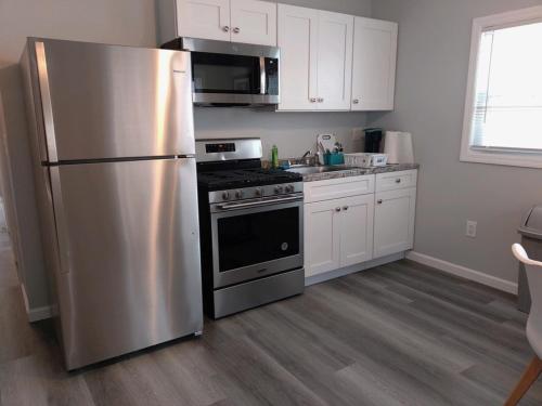 una cucina con frigorifero in acciaio inossidabile e armadietti bianchi di Dupont Beach House B a Seaside Heights
