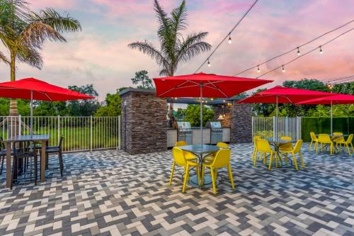 a patio with tables and chairs and red umbrellas at Home2 Suites By Hilton Vero Beach I-95 in West Vero Corridor