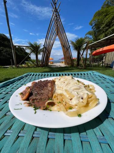a plate of pasta and meat on a table at Pousada Cantinho da Praia in Paraty