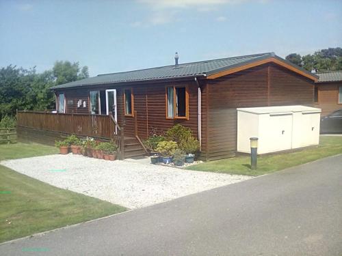 a wooden house with a driveway in front of it at LakeView Lodge Trevella Park in Crantock
