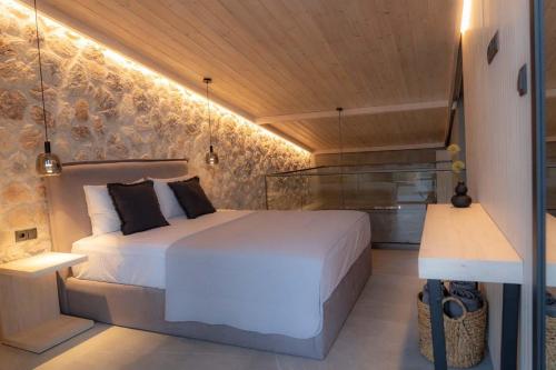 ein Schlafzimmer mit einem weißen Bett und einer Steinmauer in der Unterkunft SUNRISE VILLAS PLATAMON in Platamonas