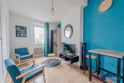 uma sala de estar com paredes azuis e uma mesa e cadeiras em L'Améthyste City WIFI em Perpignan