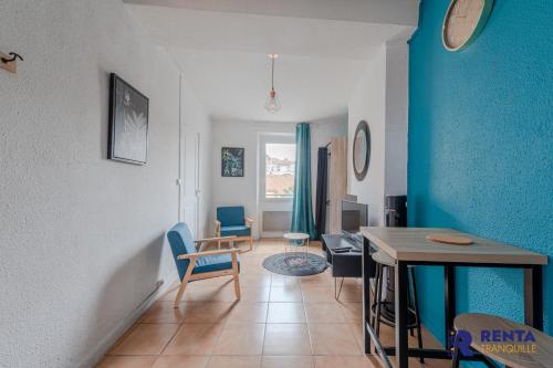 uma sala de estar com uma mesa e uma parede azul em L'Améthyste City WIFI em Perpignan
