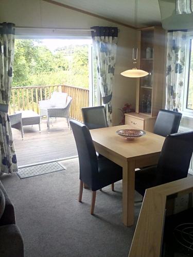 a dining room with a table and chairs and a deck at LakeView Lodge Trevella Park in Crantock