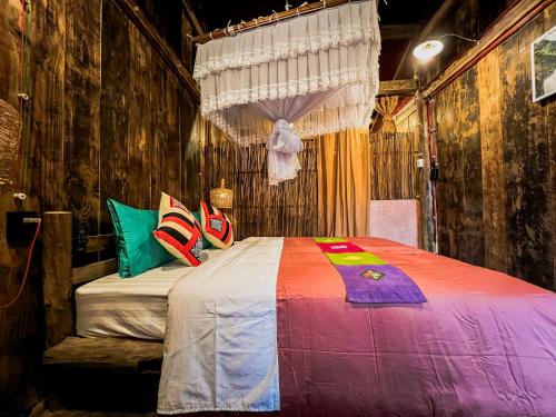 a bedroom with a bed with colorful sheets and pillows at Dinh Đá H'Mông - Karsterly Rock Lodge in Dồng Văn