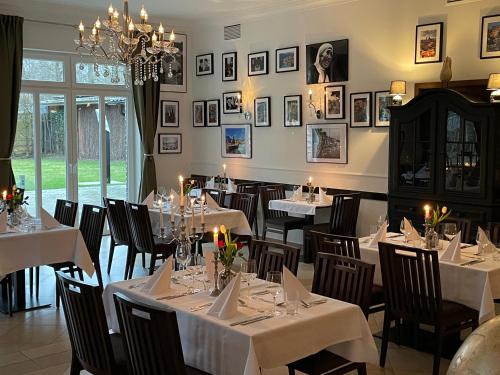 a restaurant with white tables and chairs and a chandelier at dS Hotel Restaurant Gronau in Gronau