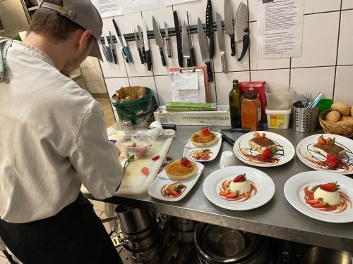 a chef preparing food in a kitchen with plates of food at dS Hotel Gronau in Gronau