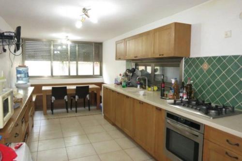 eine Küche mit Holzschränken und einer Arbeitsplatte in der Unterkunft Maison herzliyah pitouach 5 minutes à pied la plage in Herzlia