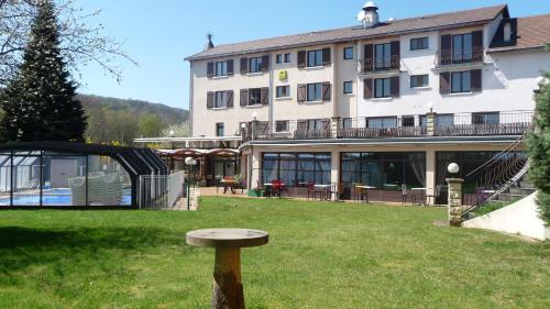 a bench in the grass in front of a building at Logis La Rose Des Vents in Volvic