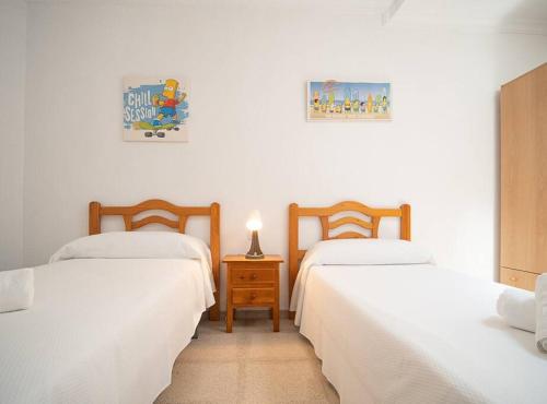 Habitación con 2 camas y mesa con lámpara. en SibsSanlucar Albero - Ideal Familias - Centro - Playa Piletas en Sanlúcar de Barrameda