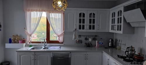 a kitchen with white cabinets and a sink and a window at Ayliya hause in Akcaabat