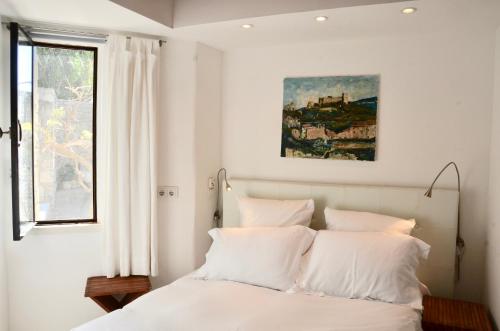 een slaapkamer met een bed met witte lakens en een raam bij maison bertuli Oliviers Aircon, heated saltwater Pool, 2 Bedrooms in Oppède