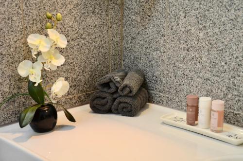 een wastafel in de badkamer met een vaas met bloemen en handdoeken bij maison bertuli Oliviers Aircon, heated saltwater Pool, 2 Bedrooms in Oppède